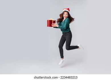 Full length Asian woman in casual green sweater holding a gift box and jumping in air on isolated grey background. Happy anniversary or new year festival concept. - Powered by Shutterstock