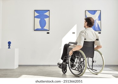 Full length back view of man using wheelchair looking at paintings in accessible art gallery or museum lit by sunlight copy space  - Powered by Shutterstock