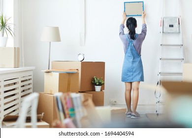 Full Length Back View Portrait Of Young Asian Woman Decorating New Home While Moving In To New House Or Apartment, Copy Space