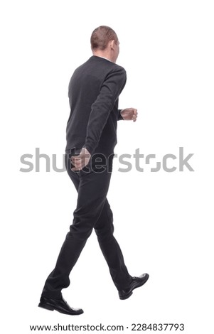 full length back view portrait of a young casual man walking away from the camera