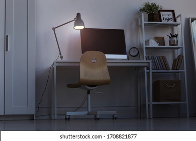 Full Length Background Image Of Home Office Workplace At Night, With Focus On Computer Desk Lit By Dim Lamp Light, Copy Space