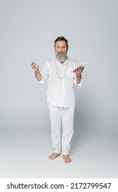 Full Length Of Barefoot Spiritual Guru Holding Digital Tablet On Grey