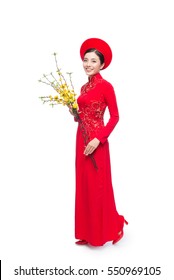 Full length of a beautiful Asian woman on traditional festival costume Ao Dai holding Hoa Mai tree (Ochna Integerrima) flower. Tet holiday. Lunar New Year.