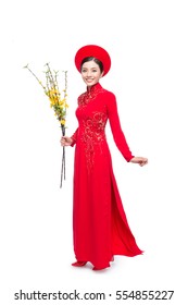 Full length of a beautiful Asian woman on traditional festival costume Ao Dai holding Hoa Mai tree (Ochna Integerrima) flower. Tet holiday. Lunar New Year.
