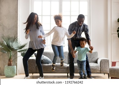 Full length black African whole family have a fun. Married couple with little kids toddler son preschool daughter dancing moving in living room at new home. Happy family spend time together concept - Powered by Shutterstock