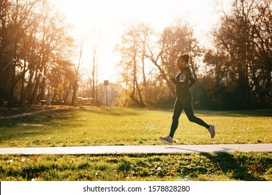 Full length of black sportswoman jogging in nature. Copy space.  - Powered by Shutterstock