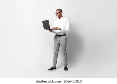 Full Length Of Black Young Business Man Holding A Laptop Over Gray Background Professional Concept.