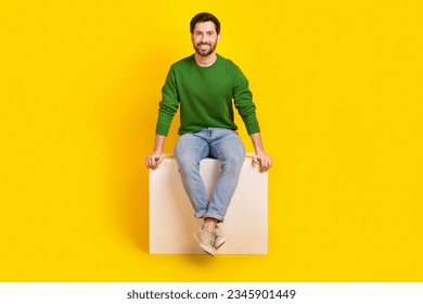 Full length body photo of cheerful young satisfied marketolog businessman guy sitting white box podium isolated on yellow color background