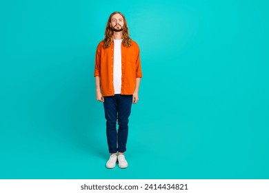 Full length body photo of confident blonde hair guy in orange shirt blue pants standing alone isolated over aquamarine color background - Powered by Shutterstock