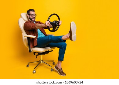 Full Length Body Photo Of Happy Fooling Man In Chair Keeping Steering Wheel Pretending Car Driver Isolated Vivid Yellow Color Background