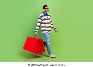 Full length body photo of man brand store advert billboard walking bring bags packages look mockup isolated on green color background