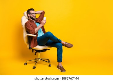 Full length body photo of smiling freelancer keeping smartphone social media sitting in chair pause isolated vibrant yellow color background - Powered by Shutterstock