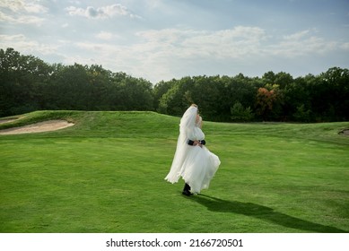 Full Length Body Portrait Of Young Bride And Groom Dancing On Golf Course, Back View. Happy Wedding Couple On Green Grass, Copy Space