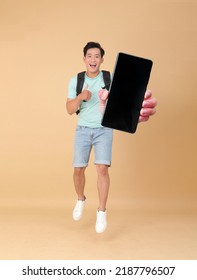 Full Length Body Portrait Of A Young Handsome Cheerful Asian Male Student, Hold A Smart Phone To Show The Screen, Concept Of App Introduction Or Promote, Isolated On Beige Background