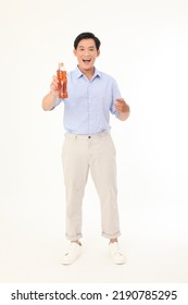 Full Length Body Portrait Of A Young Handsome And Cheerful Asian Adult Man, Hold A Drinking Bottle Of Tea, Excited And Full Of Energy, Isolated On White Background. Concept Of Soft Drink Advertising. 