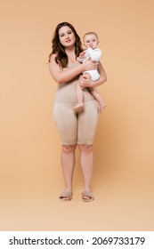 Full Length Of Body Positive Mother Holding Baby Daughter On Beige Background