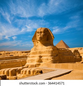 Full length body profile of Great Sphinx including head, feet with pyramid of Menkaure in background on a clear, blue sky day in Giza, Egypt empty with no people. Copy space