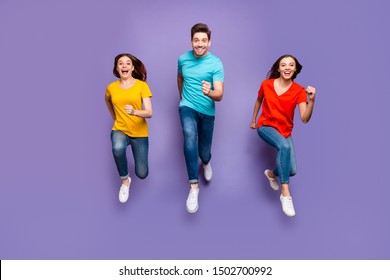 Full Length Body Size Front View Photo Of Group Of Three Crazy Emotional Hipsters Models Running To You Wearing Yellow Blue T-shirts Isolated Violet Background