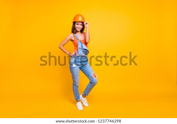 Full length body size of her she nice cute\
cheerful lovely lady wearing jeans denim overall casque isolated\
over bright vivid shine yellow\
background