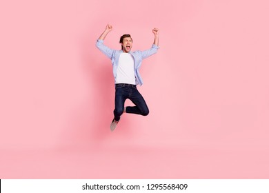 Full length body size photo of jumping high crazy cheer he his him handsome glad yelling loudly arms raised wearing casual jeans checkered plaid shirt isolated on rose background