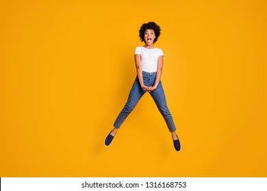 Full length body size photo jumping high beautiful she her lady screaming shouting yelling loud voice unexpected win wearing casual jeans denim white t-shirt clothes isolated yellow background