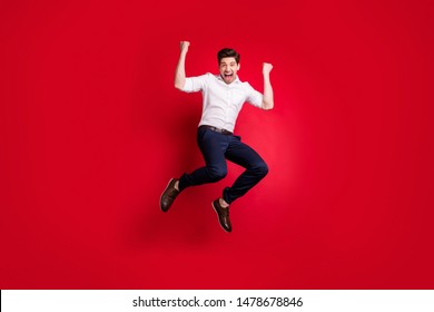 Full length body size photo of man jumping with happiness dressed formally while isolated with red background