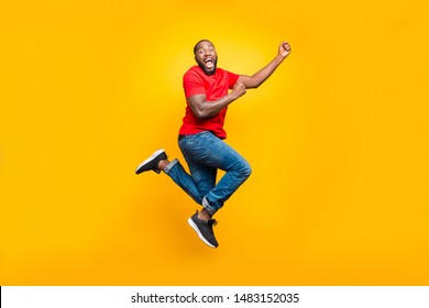 Full Length Body Size Photo Of Black Man Wearing Red T-shirt Having Caught Something Invisible And Now Dragging It While Isolated With Yellow Vivid Background