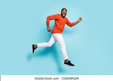 Full length body size photo side profile of man mixed-race expressing positive emotions wearing sneakers white trousers pants running jumping to discounts isolated vivid blue color background
