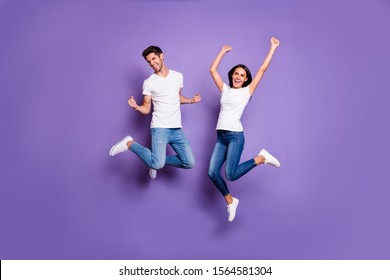 Full Length Body Size Photo Of Cheerful Excited Positive Ecstatic Jumping People In Jeans Denim White T-shit Footwear Expressing Emotions Isolated Pastel Violet Color Background