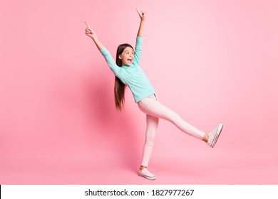 Full Length Body Size Photo Of Playful Small Girl Pointing Up With Fingers Stepping Forward Smiling Isolated On Pink Color Background