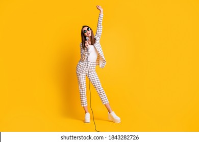 Full Length Body Size Photo Of Girl Holding Mic Singing Keeping Hand Up Smiling Wearing Sunglass Isolated On Vibrant Yellow Color Background