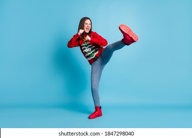 Full length body size photo of funny female student pretending to fight karate keeping one leg up shouting loudly wearing xmas outlook isolated on blue color background