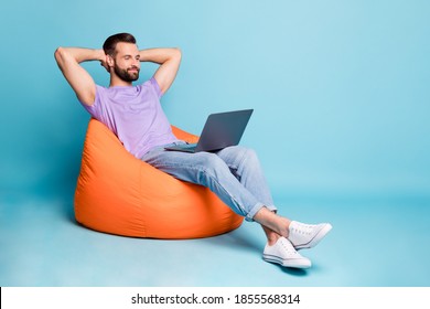Full length body size photo of bearded programmer chilling during break in orange beanbag isolated on vivid blue color background - Shutterstock ID 1855568314