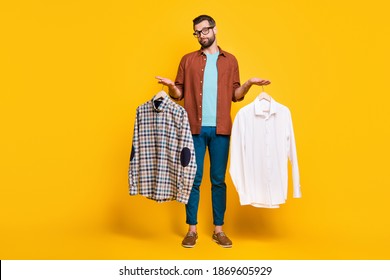 Full length body size photo of bearded consumer keeping two shirts comparing deciding isolated on bright yellow color background - Powered by Shutterstock