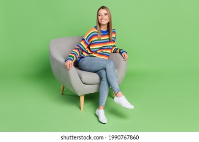 Full length body size photo smiling girl sitting in grey chair looking copyspace isolated pastel green color background