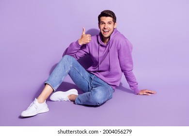 Full length body size photo man smiling showing like sign sitting on floor isolated pastel violet color background