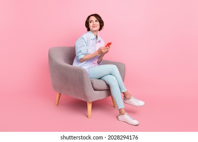 Full length body size photo woman sitting browsing internet on smartphone looking copyspace isolated pastel pink color background - Shutterstock ID 2028294176