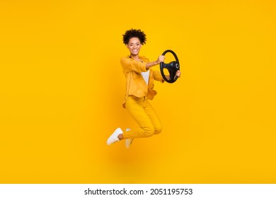 Full length body size photo woman jumping keeping steering wheel isolated vivid yellow color background