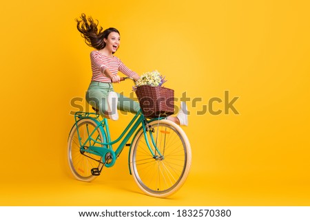 Full length body size photo of funny girl shouting riding bicycle keeping legs up isolated on vivid yellow color background