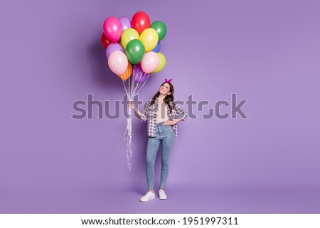Full length body size photo of girl keeping colorful balloons in headband checkered shirt jeans isolated on vibrant violet color background