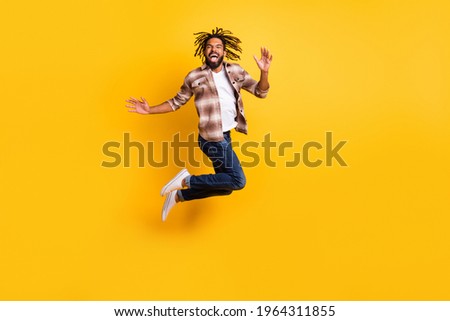 Full length body size photo of man jumping high wearing casual clothes laughing isolated on vivid yellow color background