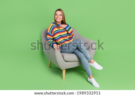 Full length body size photo smiling girl sitting in chair casual clothes looking empty space isolated pastel green color background