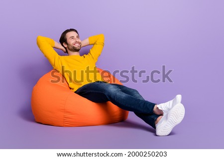 Full length body size photo man laying in beanbag chilling dreamy looking copyspace isolated pastel purple color background