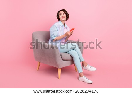 Full length body size photo woman sitting browsing internet on smartphone looking copyspace isolated pastel pink color background
