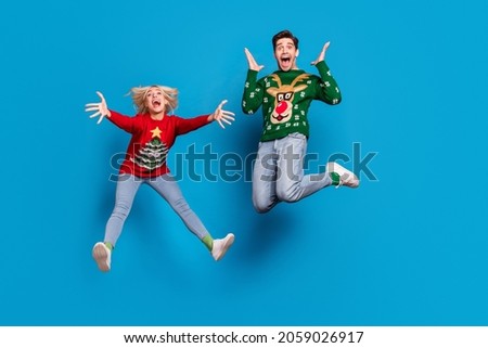 Full length body size photo couple jumping up in ugly xmas sweater shocked amazed isolated bright blue color background