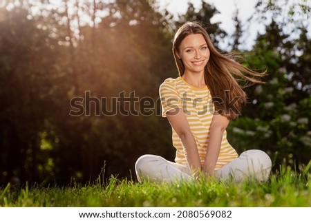 Full length body size photo smiling woman sitting on grass in green summer city park