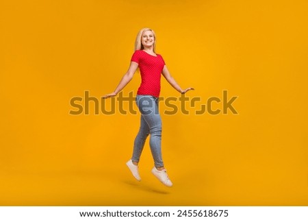 Full length body size photo woman jumping up smiling isolated vivid orange color background