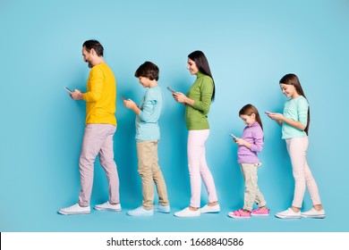 Full length body size profile side view of nice focused cheerful big full family pre-teen kids using 5g chatting communicating walking isolated on bright vivid shine vibrant blue color background
