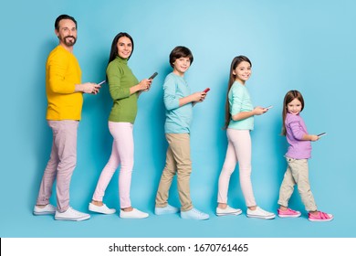 Full length body size profile side view of nice attractive glad cheerful big full family pre-teen kids using 5g device reading post walking isolated on bright vivid shine vibrant blue color background