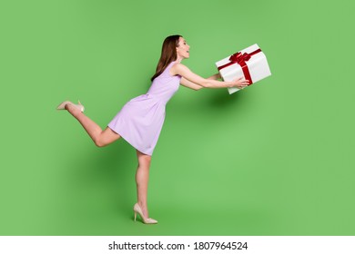 Full length body size profile side view of her she nice-looking attractive elegant cheerful cheery glad girl holding in hands giving big large giftbox occasion isolated green color background